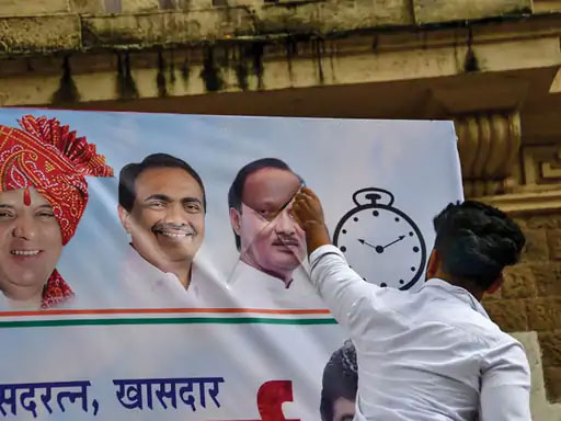 An NCP worker standing on the picture of Ajit Pawar in an NCP poster.